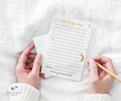 Hands holding a celestial-themed funeral memory card with a gold moon and stars, designed for guests to share personal tributes during a memorial service.